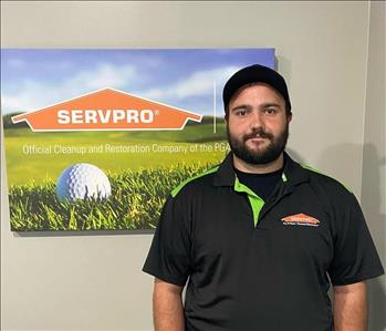 A male SERVPRO employee is shown in a black shirt with SERVPRO logo and hat