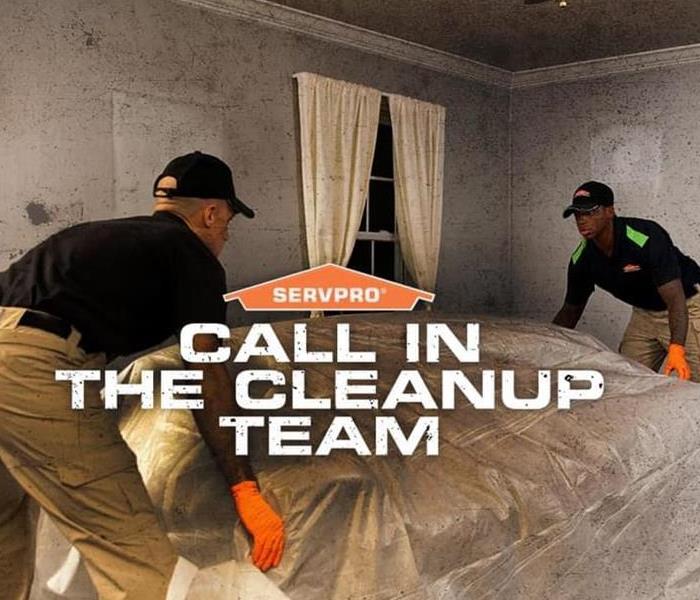 Two SERVPRO technicians are cleaning a water damaged room and the words Call in the cleanup team are shown