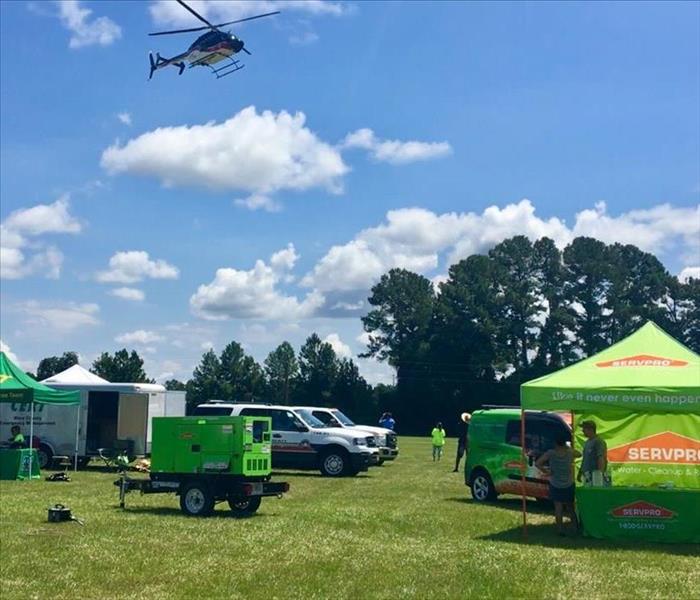 AirEvac Helicopter flys over SERVPRO tent and generator at the event.