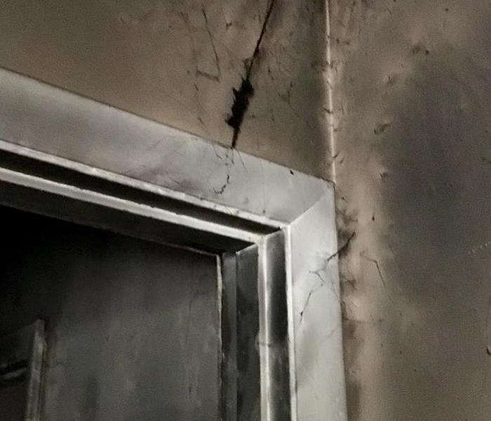 Smoke covered door frame with spiderweb like black strings.