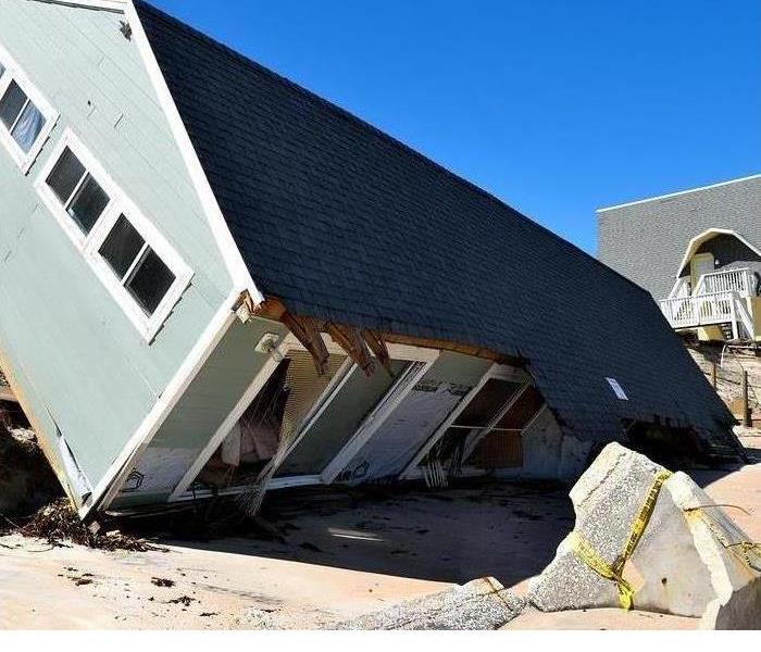A house is shown partially blown over after a storm