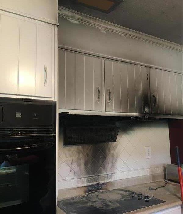 Grease fire caused white cabinets to be covered in black smoke and to be partially burnt.