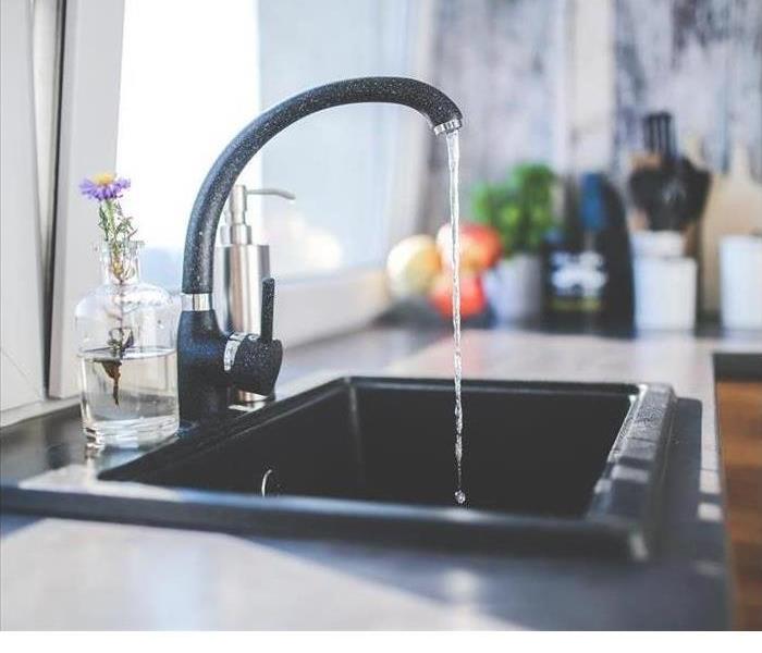 A kitchen faucet is shown with running water 